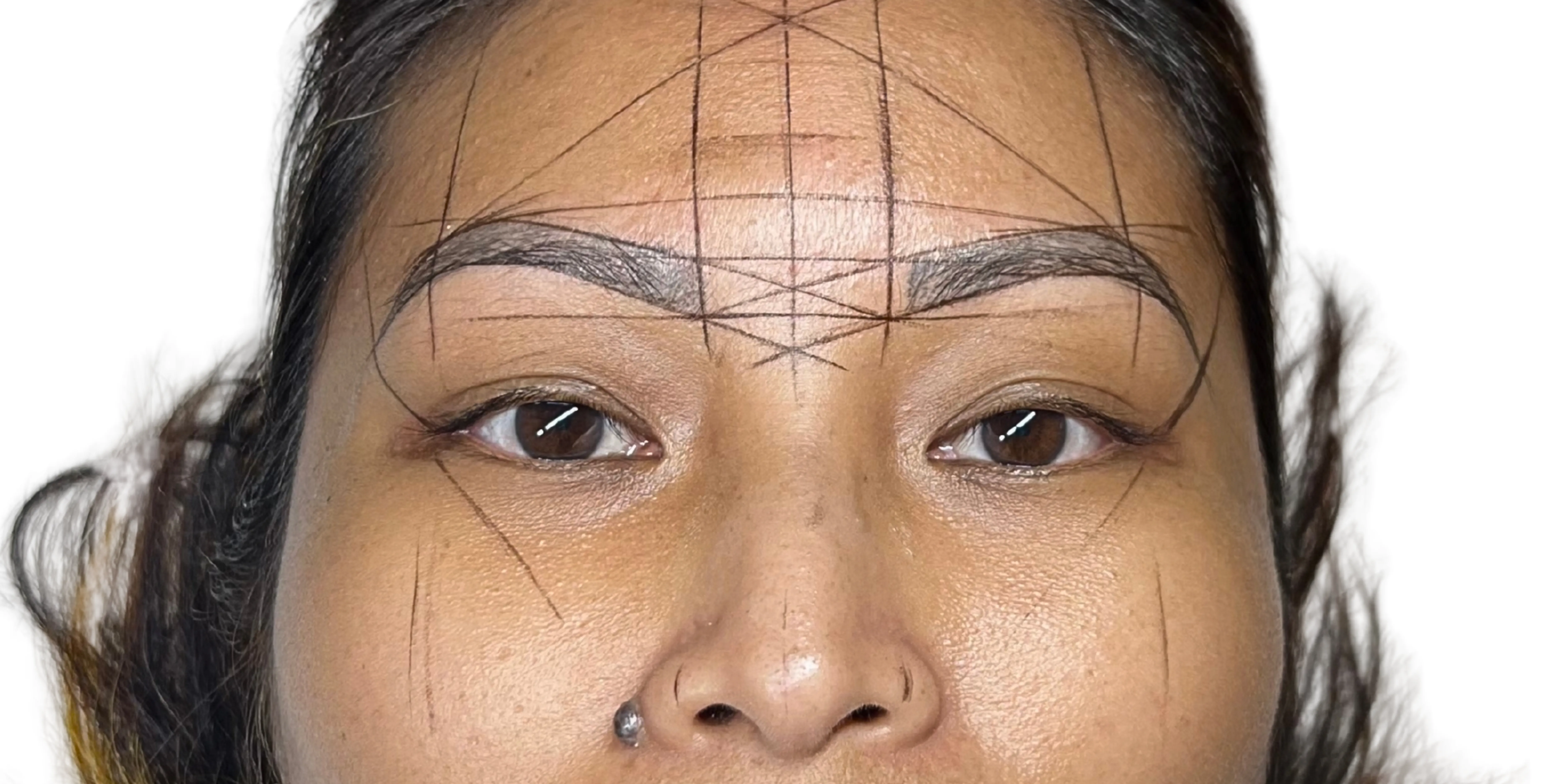 A client's face mapped for new brows — fine measuring lines drawn across the forehead, brows and cheeks