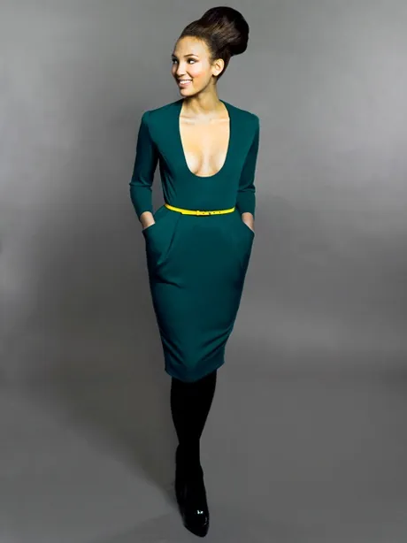 A Selahdor dress — a fitted teal dress with a deep scoop neck and a thin yellow belt